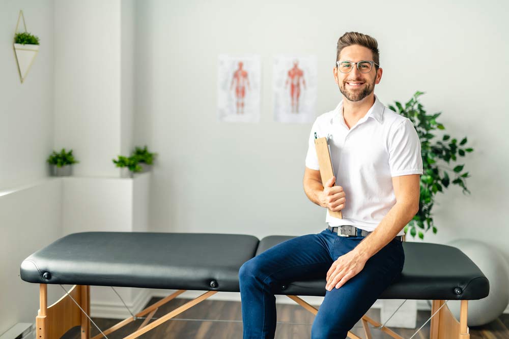 Chiropractor sitting on adjustment table in his office
